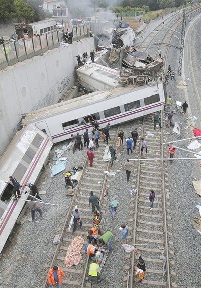 24日，救援人員在西班牙列車脫軌現(xiàn)場(chǎng)。一節(jié)車廂被強(qiáng)大的慣性拋上鐵道邊的高臺(tái)。