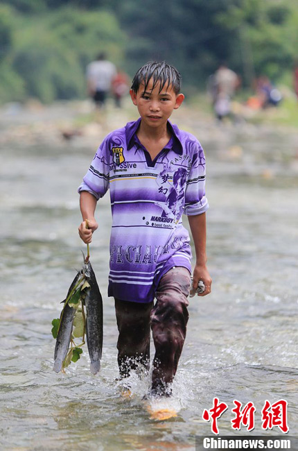 圖為7月9日，一名男孩在鬧魚節(jié)活動中抓到了兩條魚。譚凱興 攝