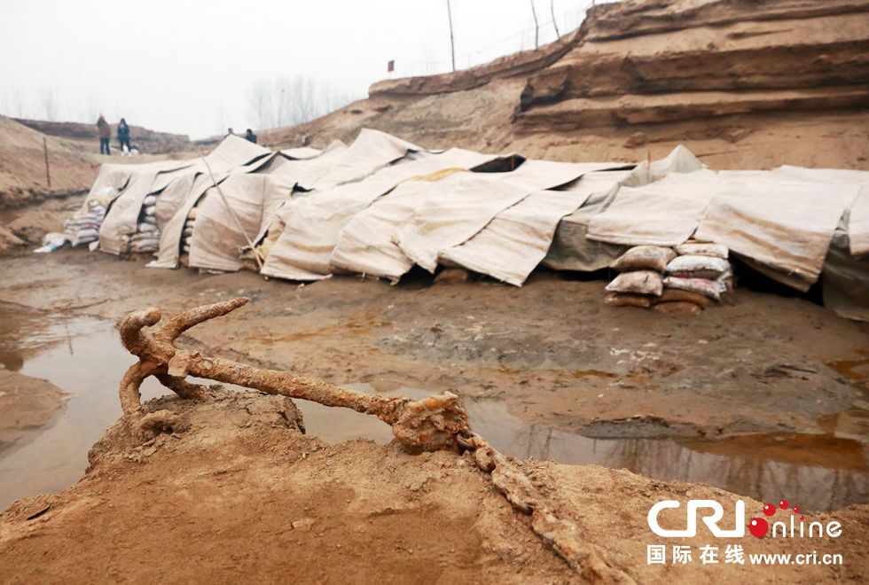 2014年1月6日，河南洛陽古沉船發(fā)掘現(xiàn)場，古沉船鐵錨從見天日，靜靜地躺在古船旁。