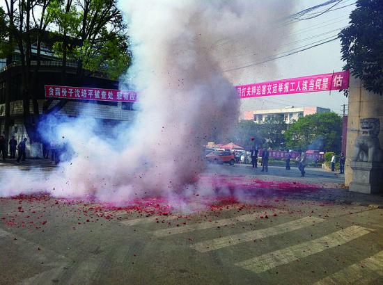 市民在普洱市主干道振興大道的金孔雀交通運(yùn)輸集團(tuán)有限公司門前燃放鞭炮，公司門前掛著“貪腐份子沈培平被查處，罪有應(yīng)得，大快人心?！钡臈l幅