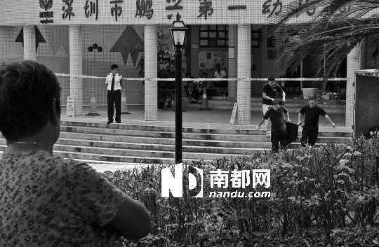 →7月19日，鵬興花園第一幼兒園門前，民警在現(xiàn)場進(jìn)行完勘查取證后，園長和保安的尸體被運(yùn)走。南都記者 徐文閣 攝