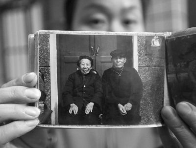 圖為孫女拿出兩位老人上世紀(jì)80年代在家門(mén)口的合影給記者看。記者楊濤 攝