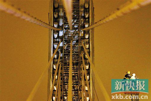 截至今日零時，男子仍未有下橋舉動。圖為公安和消防人員乘消防云梯在高空上和男子交談。