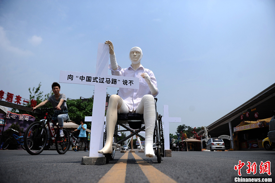 4月16日，重慶市洋人街上擺放著兩個受了傷的塑料人像“模特”，旁邊十字架上寫著向“中國式過馬路”說不