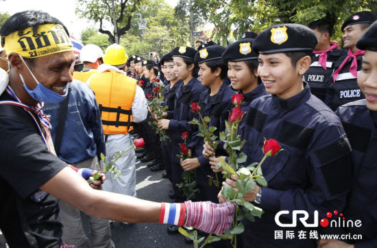 2013年12月03日,曼谷總理府與曼谷警署允許反政府示威民眾進入,雙方進入暫時“停戰(zhàn)”狀態(tài)迎接泰王生日。曼谷警察總署,女警們手持鮮花送給反政府示威民眾。圖片來源:Manish Swarup/東方IC