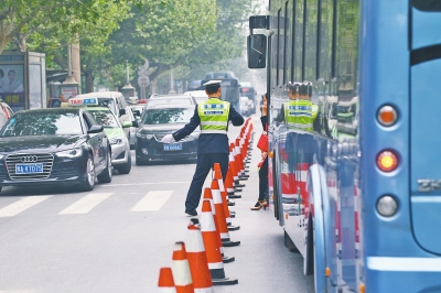 省人民醫(yī)院南門(mén)的路中間擺放反光錐，交警示意由西向東車(chē)輛從前方繞行。