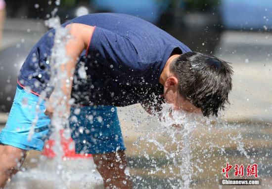 5月29日，一名小孩將頭伸向北京街頭的噴泉以降溫祛暑。