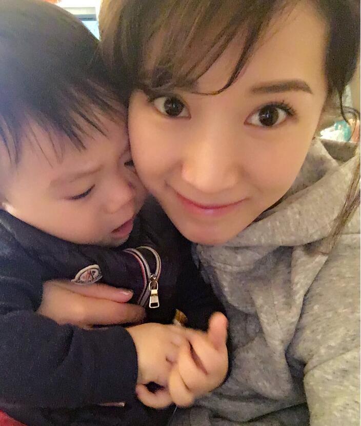 照片中李念狂吻兒子，小寶貝自顧自地玩著。