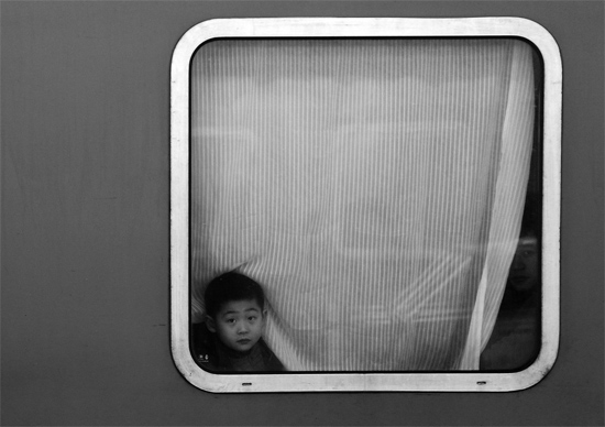 一個孩子把頭伸向窗外，他想再看送別的親人一眼