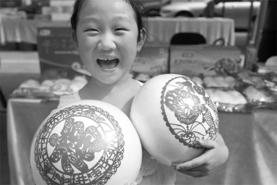 在2013河南食品安全宣傳周活動(dòng)現(xiàn)場(chǎng)，一個(gè)小女孩抱著參展的特色大饅頭樂開了花
