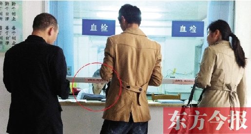 昨日，鄭州市二七區(qū)疾控中心辦證大廳，血檢窗口內(nèi)一名女工作人員，邊接受辦證者咨詢邊看報紙
