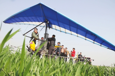 　　4月12日，在武陟縣北郭鄉(xiāng)韓余村，一架三角翼動(dòng)力滑翔機(jī)在對(duì)小麥進(jìn)行農(nóng)藥噴灑作業(yè)。為提升農(nóng)業(yè)生產(chǎn)的