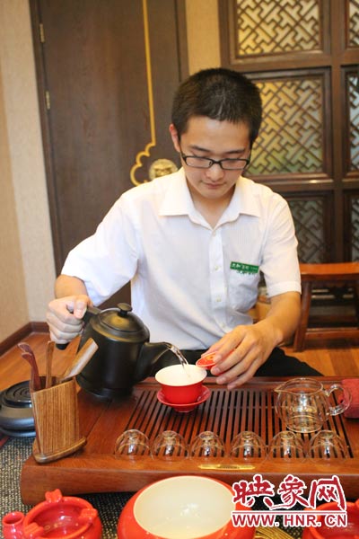 1、水壺里的水煮沸，李克勤把茶葉放進茶荷里，準備溫杯沖茶