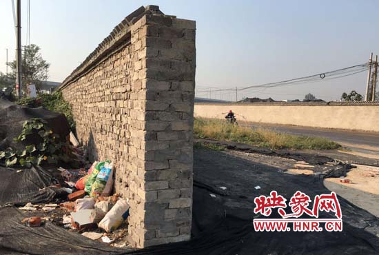 一墻之隔，一邊是道路，一邊是垃圾和荒草，市民質(zhì)疑其為遮羞墻。