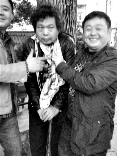 兩名接訪人員與患有癌癥的訪民段新德合影時，面帶笑容擺出勝利的手勢。