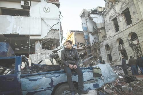 埃及曼蘇拉市警察局24日遭汽車炸彈襲擊，被疑是穆兄會的報(bào)復(fù)。圖為一名男子在被炸毀的警察局前。