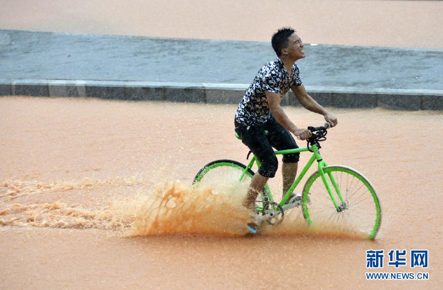 5月11日，一名行人在深圳街頭冒雨騎行。