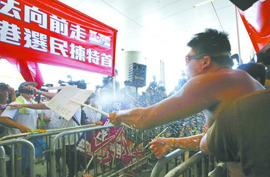 17日，在香港立法會(huì)外，一名反對(duì)政改的男子向支持派人群投擲標(biāo)牌。