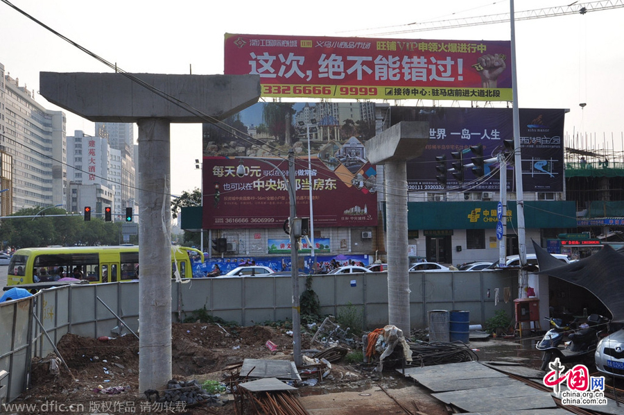 過街天橋一側(cè)的橋樁早已打好,可是對(duì)面的郵政銀行網(wǎng)點(diǎn)依舊在照常營(yíng)業(yè)。