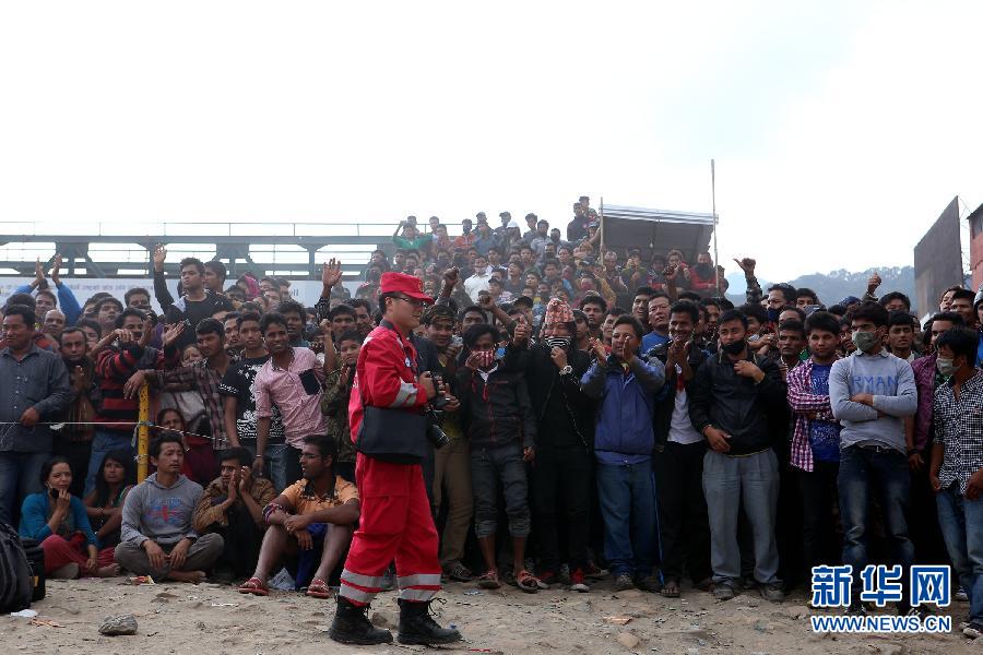 圍觀的尼泊爾民眾在中國國際救援隊(duì)成功搜救出幸存者后向搜救隊(duì)員歡呼致意。