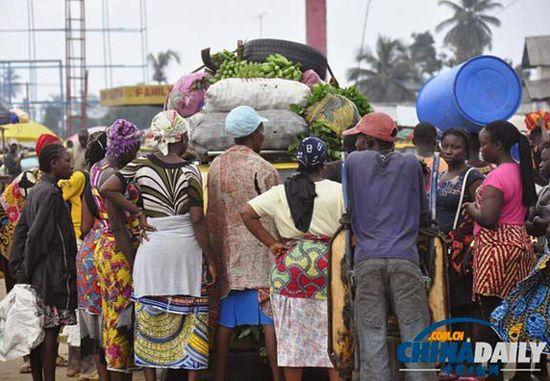 當(dāng)?shù)貢r間2014年8月14日，利比里亞蒙羅維亞，市場里的商人們圍著一輛汽車。
