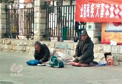 工人體育場(chǎng)北路，兩位乞討者路邊乞討，并輪流扮成“病人”（躺地者）。 央視截圖