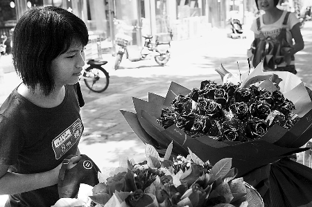 鄭州市農(nóng)業(yè)路一家花店擺放的玫瑰花吸引著一位過往女孩。